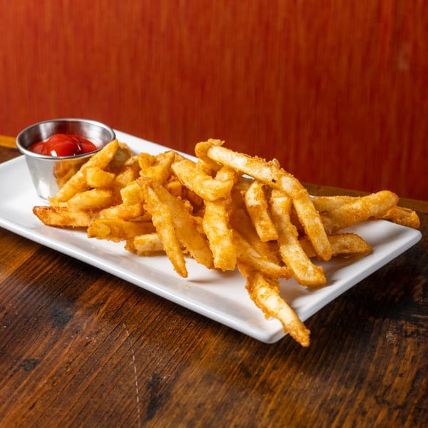 Crispy golden french fries on a white rectangular plate with a side of ketchup.