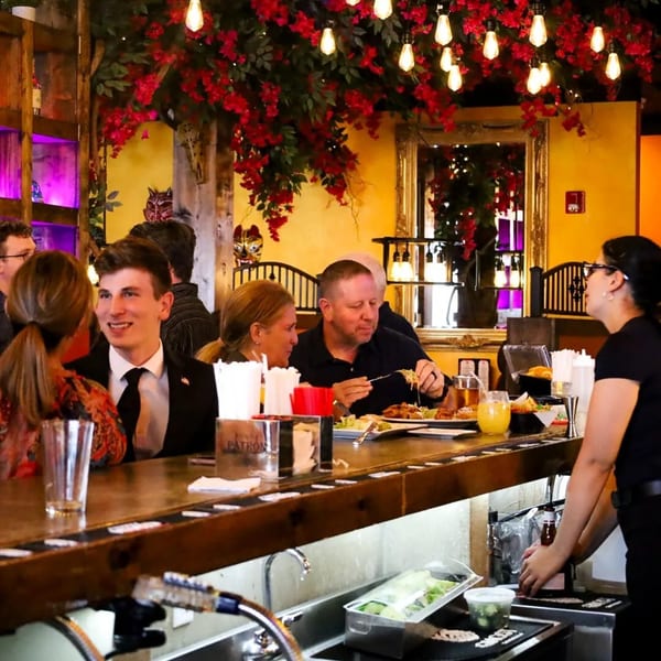 Patrons enjoying food and drinks at the bar of Frida's Mexican Grill, with a bartender working.
