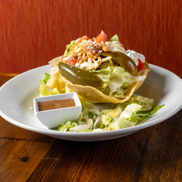 Frida's Mexican Grill taco salad with chicken, lettuce, tomatoes, cheese, guacamole, and jalapeños.