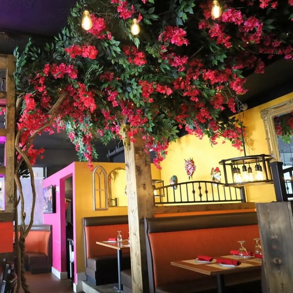 Restaurant interior with red floral ceiling decor, yellow walls, and orange booth seating.