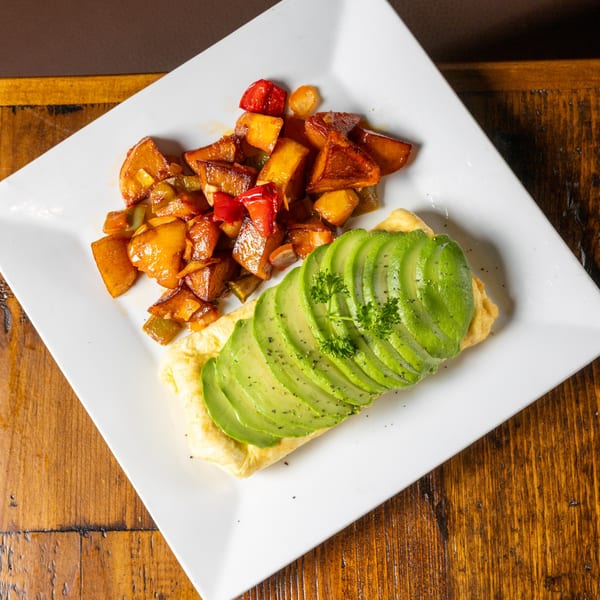 Frida's Mexican Grill's omelet topped with sliced avocado and a side of roasted potatoes.