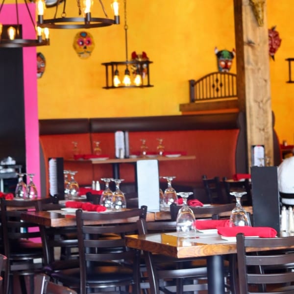 Frida's Mexican Grill dining room with colorful decor, set tables, and red booth seating.