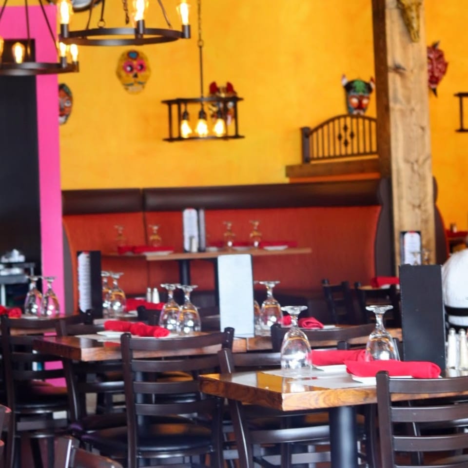 Frida's Mexican Grill dining room with colorful decor, set tables, and red booth seating.